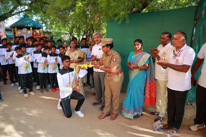 A student lights the sports meet torch as guests look on