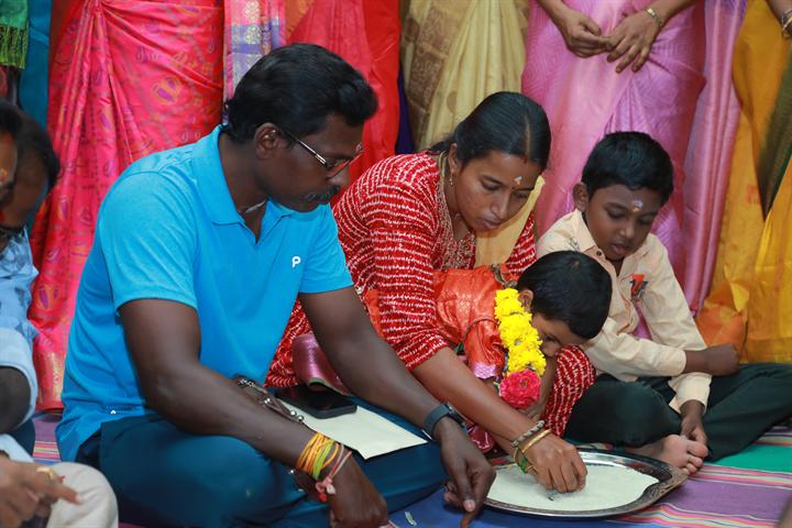 A young child writes first letters in a plate of rice at Vidyarambham